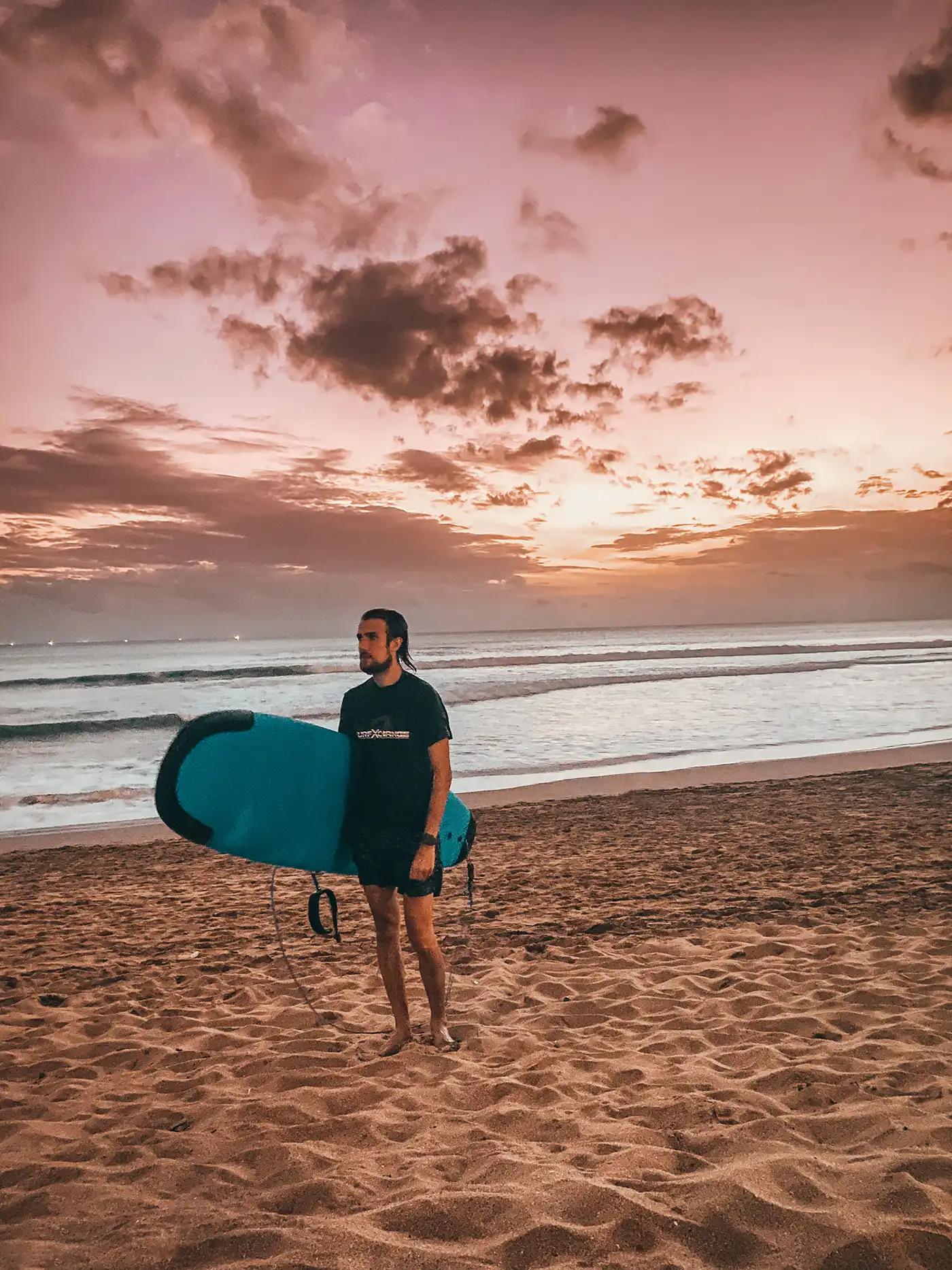 Roman carrying a surfboard at sunset